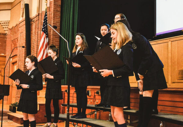 Doane Stuart students on stage in chorus, singing