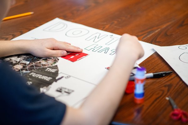 A student working on a "don't hate" sign