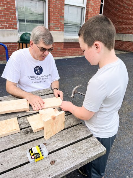 A Doane Stuart teacher wood working with a Summer Days participant